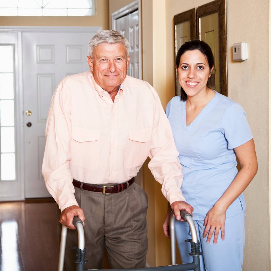 Elderly man walking with a walker next to a nurse